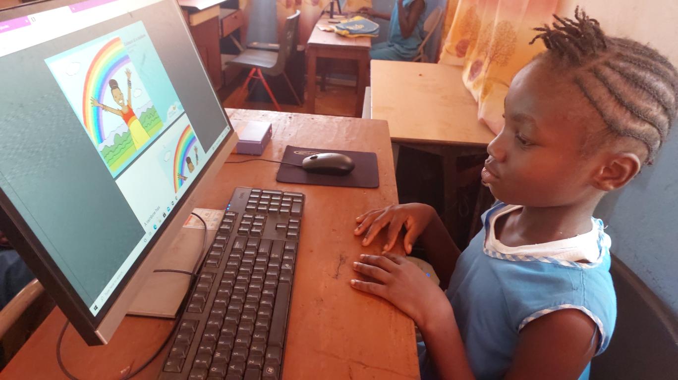 Aminata reading "Colors of the Rainbow" on her computer