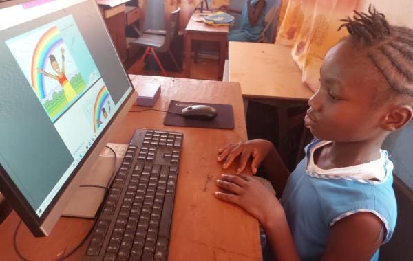 Aminata reading "Colors of the Rainbow" on her computer