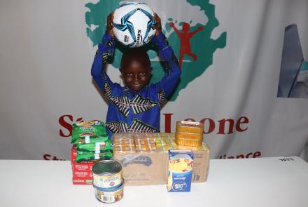 Isaiah with a big smile showing his new soccer ball and holiday gift