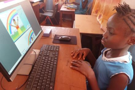 Aminata reading "Colors of the Rainbow" on her computer